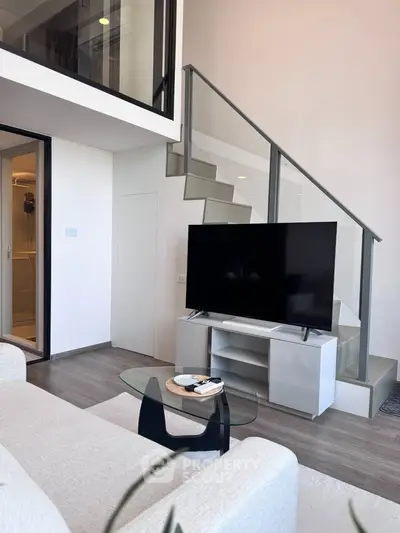Modern duplex living room with sleek staircase and large TV, perfect for stylish urban living.
