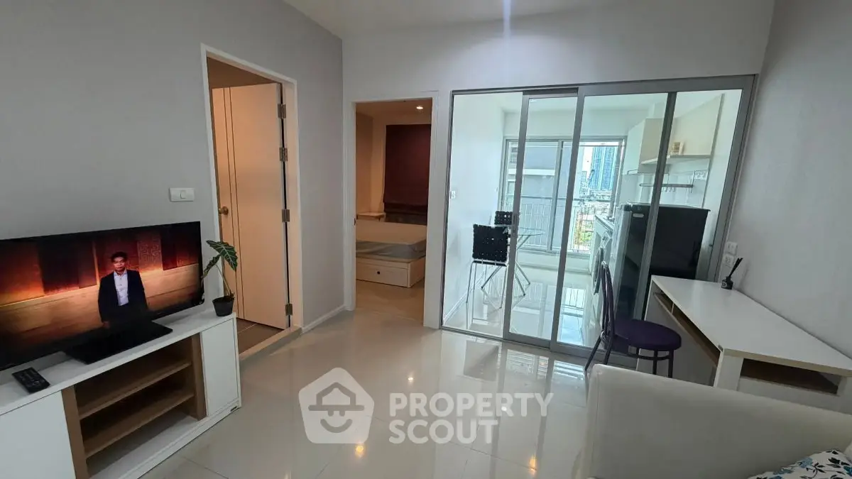 Modern living room with TV, sliding glass doors, and city view from balcony.