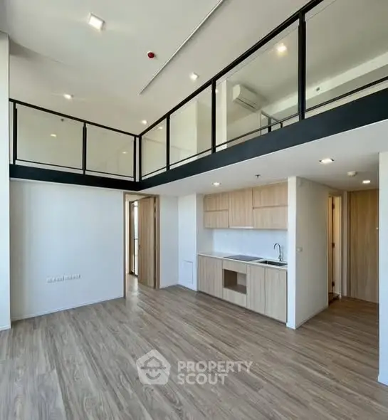 Modern loft apartment with high ceilings and open kitchen layout, featuring sleek wooden flooring and contemporary design.