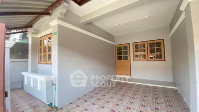 Charming covered patio with tiled flooring and wooden windows, perfect for outdoor relaxation.