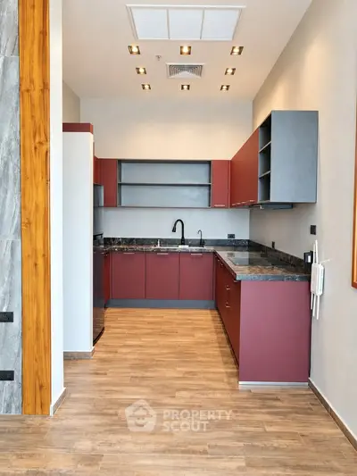 Modern kitchen with sleek cabinetry and wooden flooring in a stylish apartment.