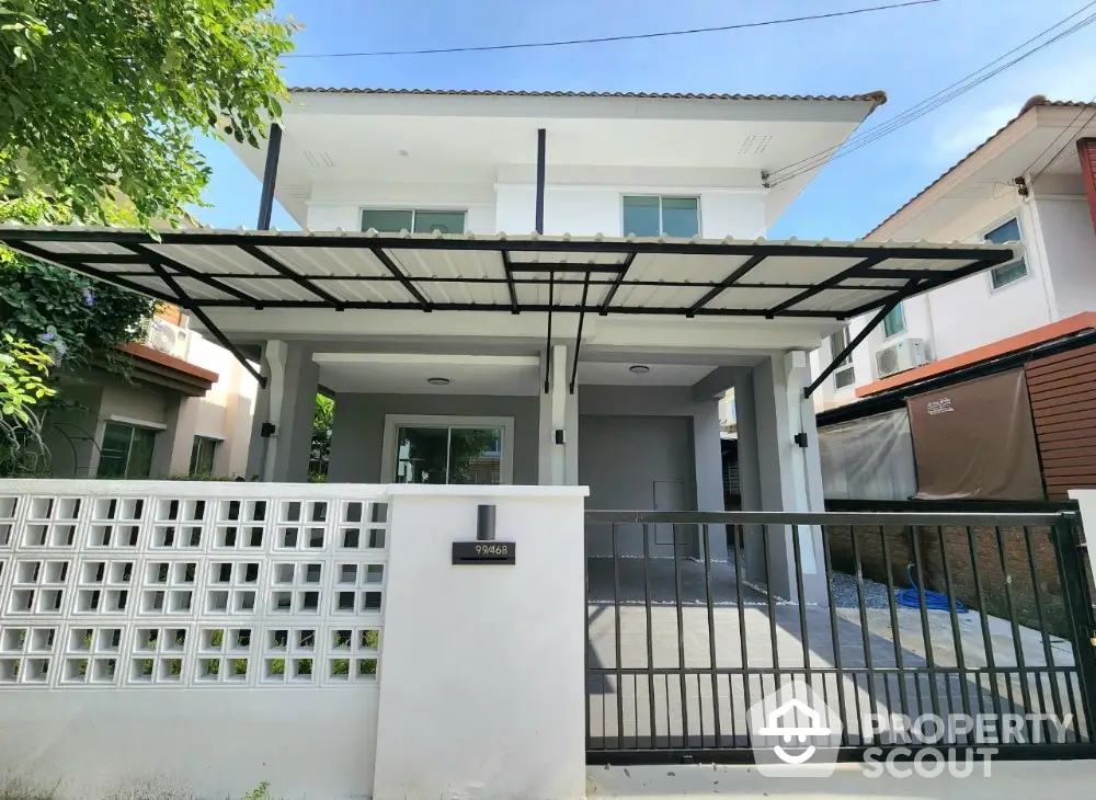 Modern two-story house with gated entrance and carport in a suburban neighborhood.