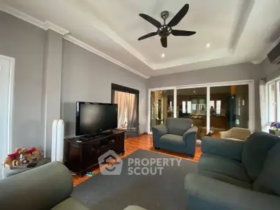 Spacious living room with modern decor and ceiling fan, perfect for relaxation.