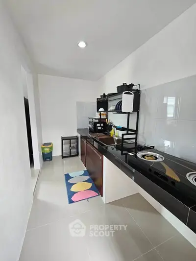 Modern kitchen with sleek black countertops and gas stove in a minimalist design.