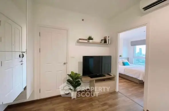 Modern apartment interior with TV and bedroom view, featuring sleek design and cozy ambiance.