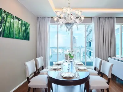 Elegant dining room with city view, featuring a round table, chandelier, and large windows.