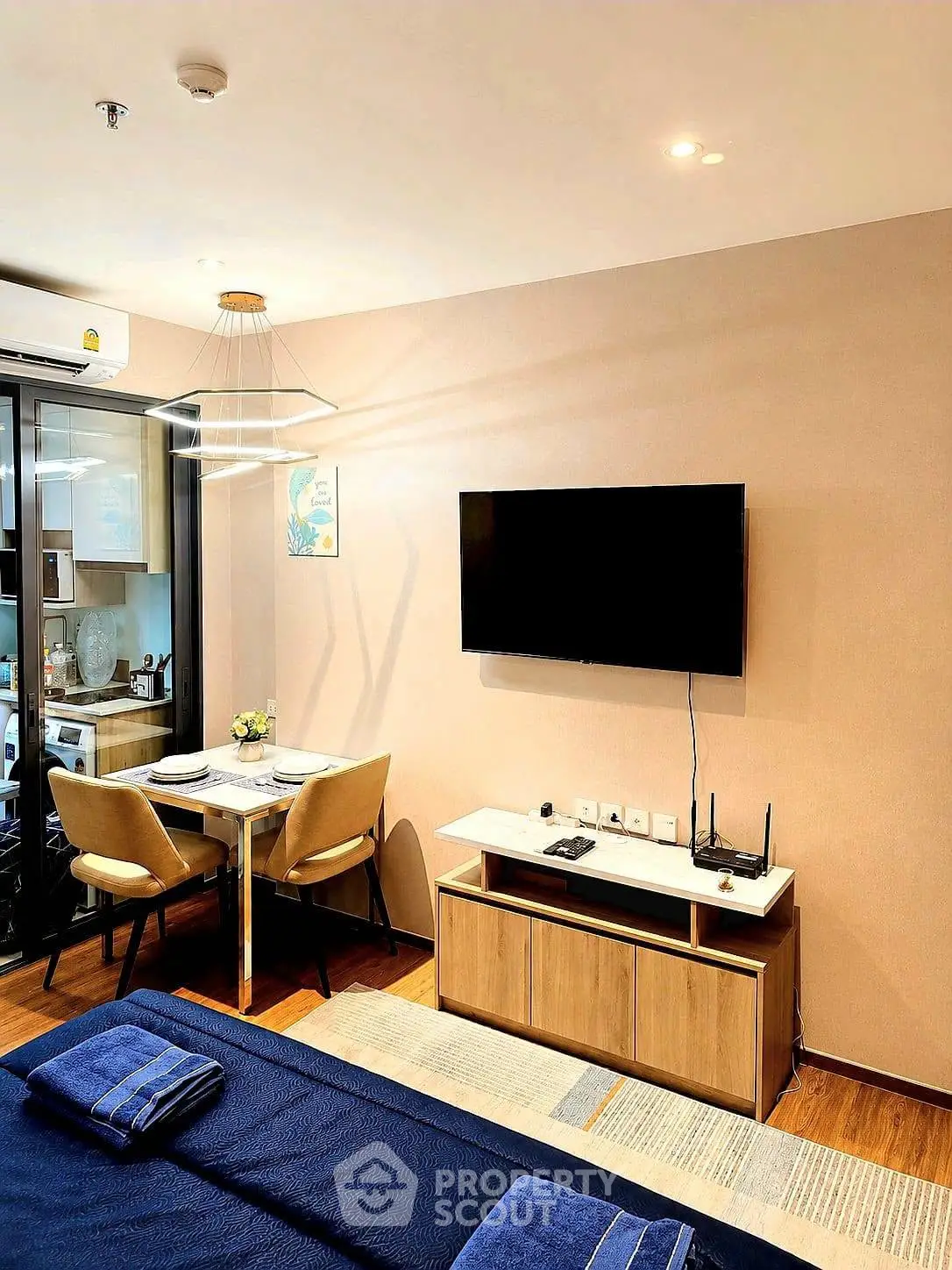Modern living room with wall-mounted TV and stylish dining area in open layout apartment.