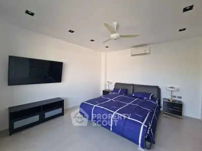 Modern bedroom with sleek design, featuring a large TV and stylish bed.