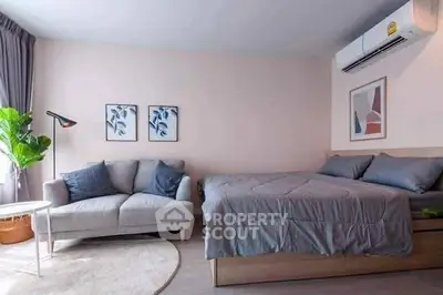 Modern studio apartment with cozy bed and stylish sofa, featuring minimalist decor and natural light.