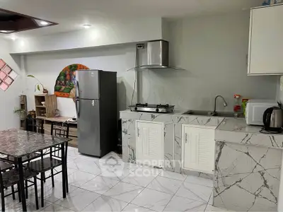 Modern kitchen with marble countertops, gas stove, and dining area in a stylish apartment.