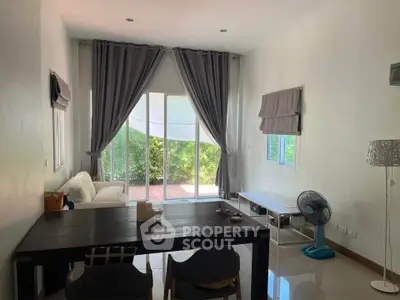 Spacious living room with large windows and garden view, featuring modern furniture and elegant curtains.