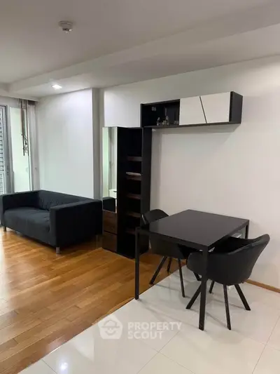 Modern living room with sleek black furniture and wooden flooring