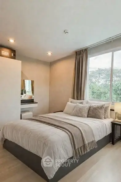 Cozy bedroom with large window and elegant decor, offering a serene and inviting atmosphere.