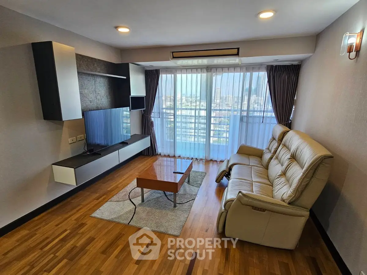 Spacious living room with modern furniture and city view through large windows.