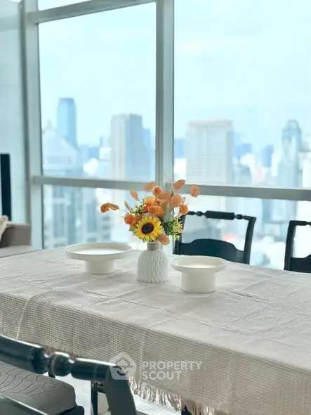 Elegant dining area with city view, featuring a stylish table setting and large windows.