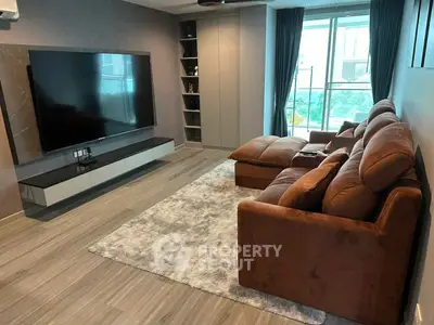 Modern living room with plush sofa and large TV, featuring sleek design and natural light.