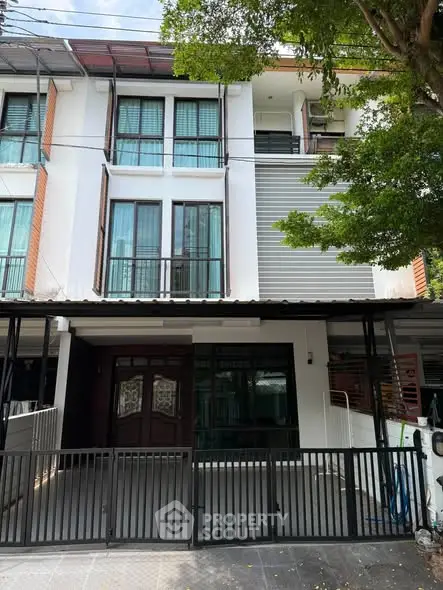 Modern three-story townhouse with gated entrance and contemporary facade.
