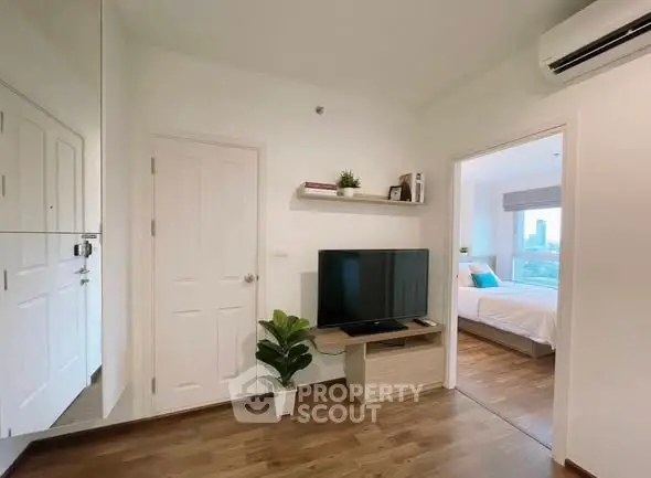 Modern living room with TV and bedroom view, featuring sleek design and natural light.