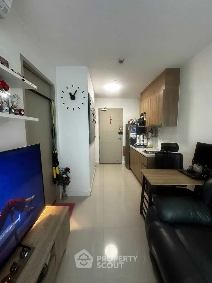 Modern living room with sleek kitchen in compact apartment, featuring stylish decor and cozy seating area.