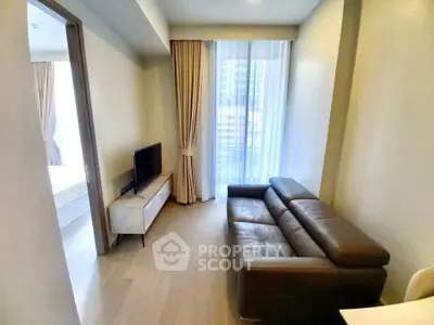 Cozy living room with leather sofa and modern TV stand, featuring floor-to-ceiling windows and elegant curtains.
