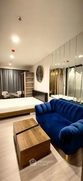 Modern studio apartment with stylish blue sofa and mirrored wall