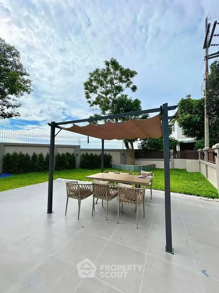 Spacious outdoor patio with modern pergola and dining set in lush garden setting.