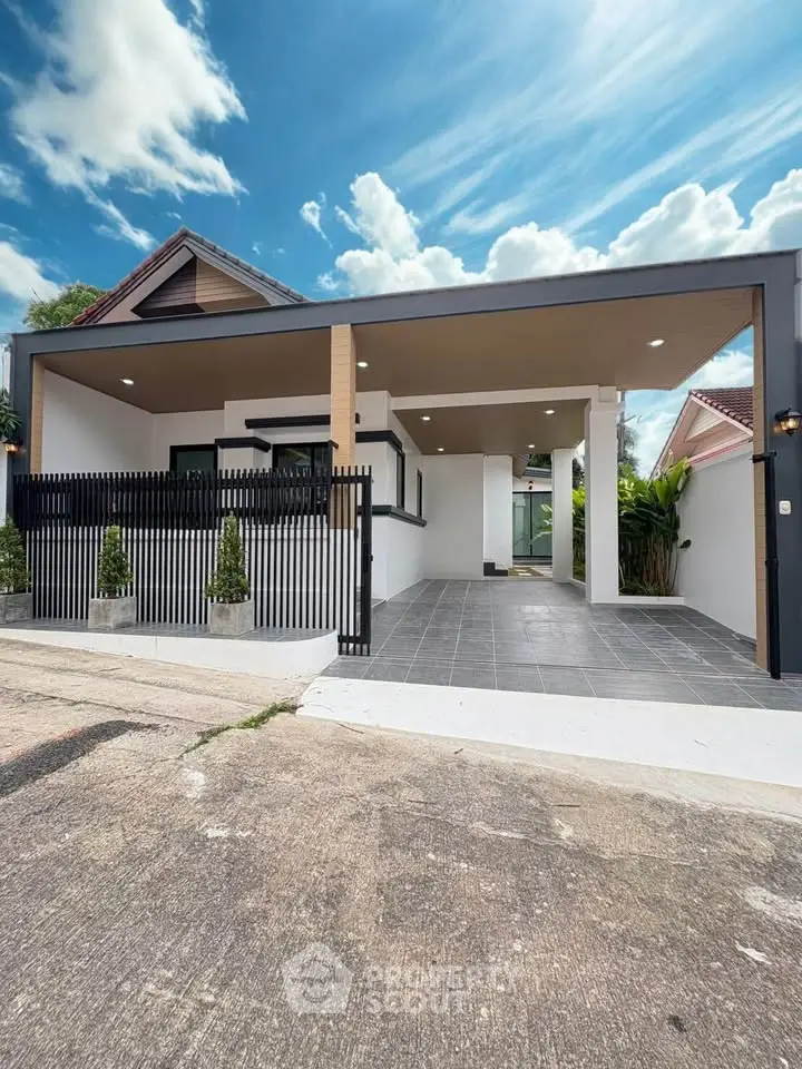Modern single-story house with sleek design and spacious carport, featuring a stylish fence and lush greenery.