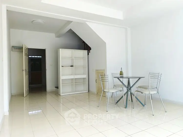 Spacious minimalist living area with modern glass table and chairs, ideal for open concept living.