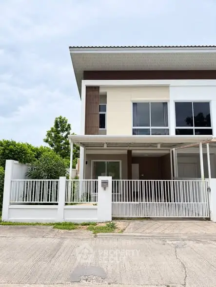 Modern two-story house with large windows and a gated front yard, showcasing contemporary architecture.