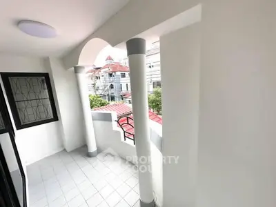 Spacious balcony with elegant columns and city view, perfect for relaxation.