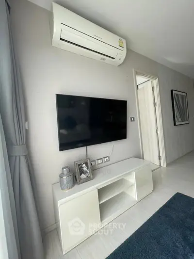 Modern living room with wall-mounted TV and air conditioning unit, sleek white furniture, and stylish decor.