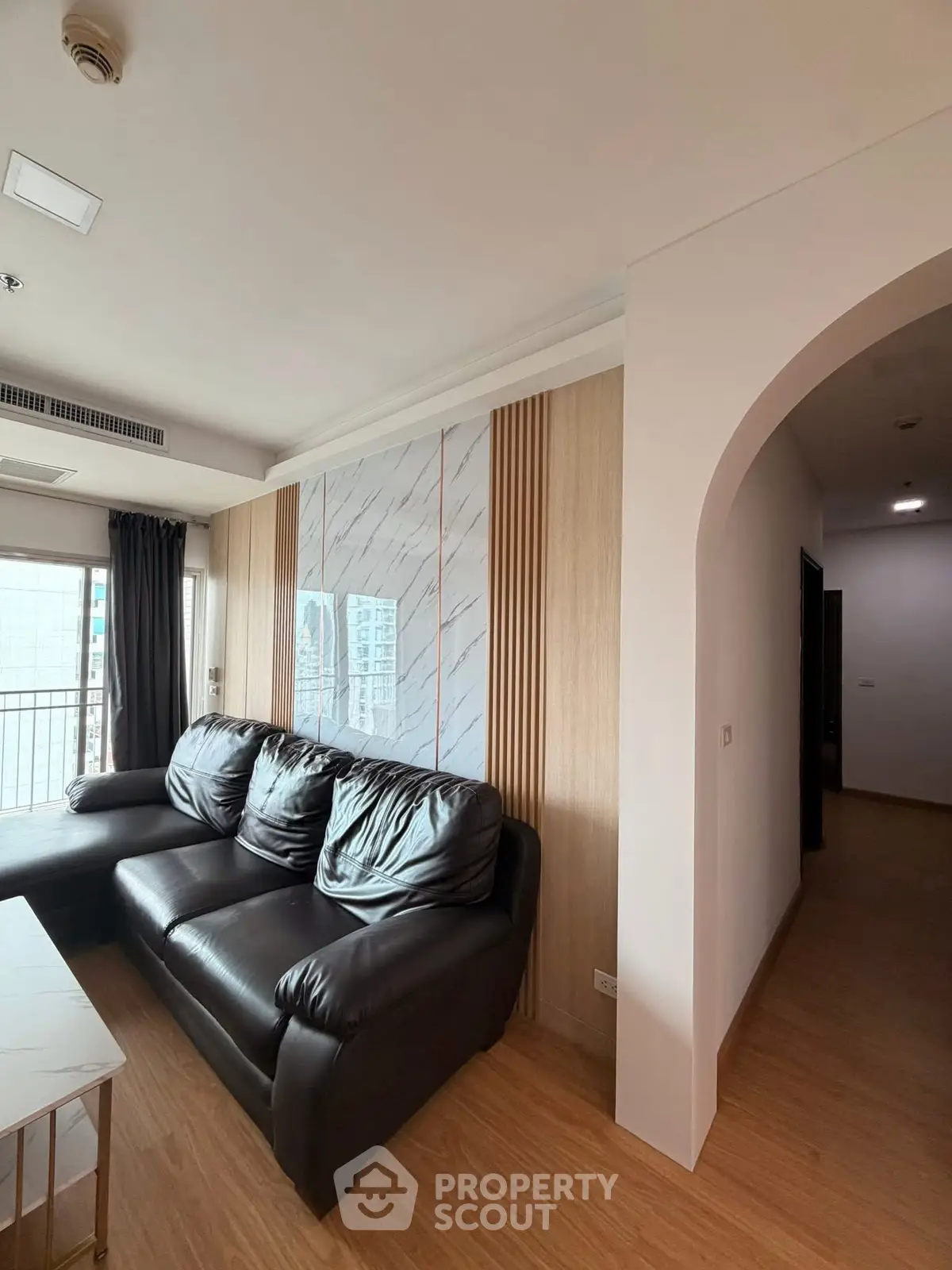 Spacious living room with modern decor and large windows offering city views.