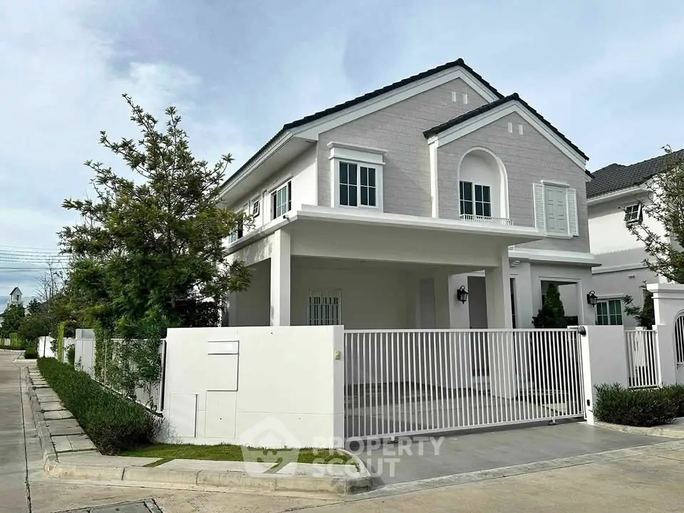 Elegant two-story house with modern design and gated driveway in a serene neighborhood.