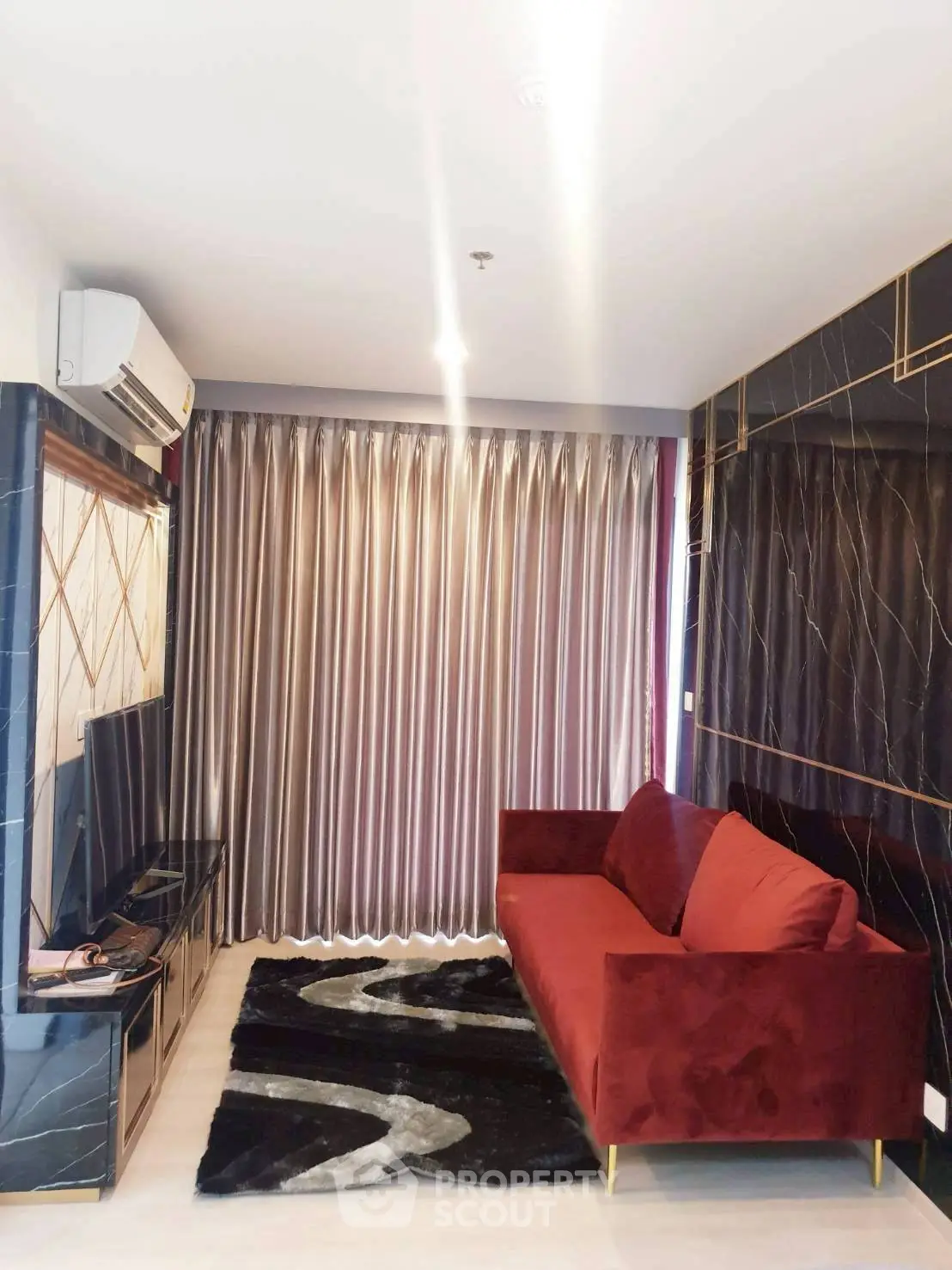 Modern living room with red sofa, stylish curtains, and sleek TV setup in a contemporary apartment.
