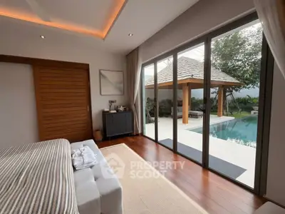 Luxurious bedroom with poolside view and elegant wooden accents in a modern villa.