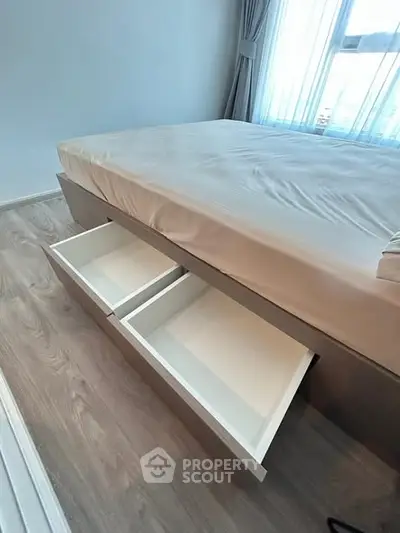 Modern bedroom with built-in under-bed storage drawers and large window.