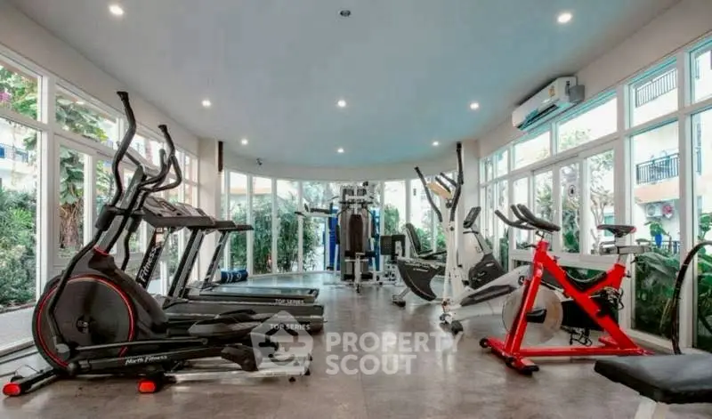 Spacious modern gym with state-of-the-art equipment and large windows for natural light.