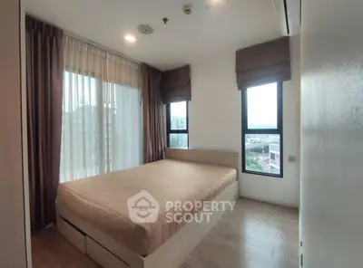 Spacious bedroom with large windows offering city views, featuring a comfortable bed and elegant curtains.