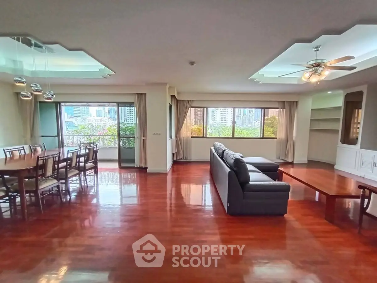 Spacious living room with hardwood floors and city view, featuring modern dining area and cozy seating.