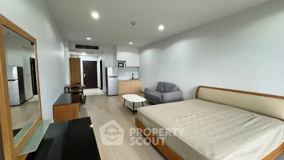 Modern studio apartment with open layout, featuring a cozy bed, compact kitchen, and stylish living area.