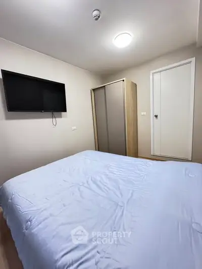 Cozy bedroom with modern wardrobe and wall-mounted TV, perfect for relaxation.
