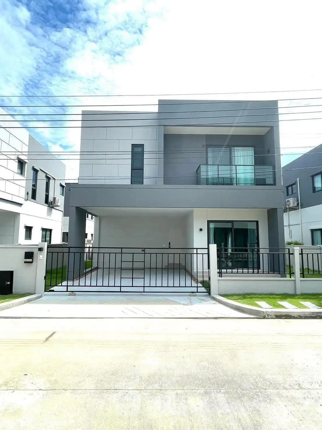Modern two-story house with sleek design and spacious balcony in a suburban neighborhood.