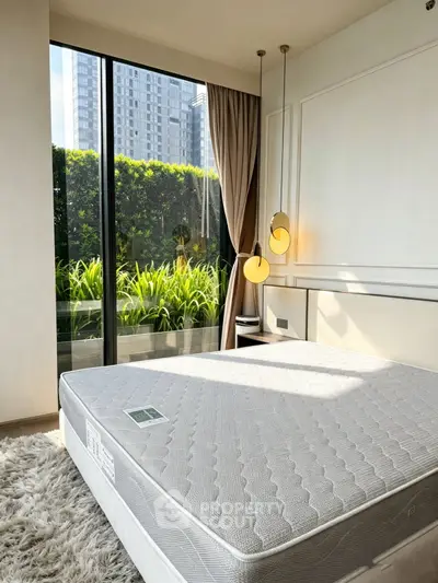Modern bedroom with large window and city view, featuring stylish lighting and lush greenery outside.