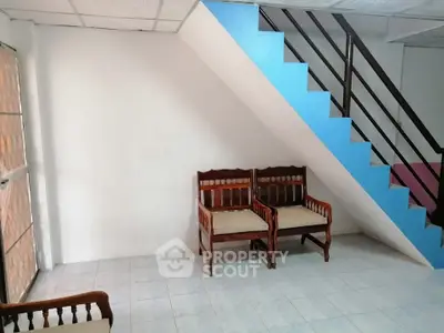 Cozy living room with staircase and wooden chairs, perfect for small gatherings.