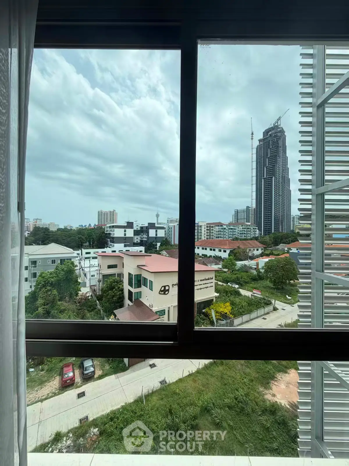 Stunning cityscape view from a high-rise window showcasing urban skyline and lush greenery.