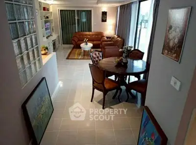 Elegant living room with leather sofas and dining area, featuring modern decor and ample natural light.