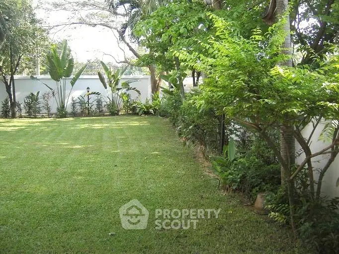 Lush green garden with manicured lawn and tropical plants, perfect for relaxation.