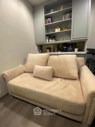 Cozy living room with plush beige sofa and built-in shelving, perfect for relaxation and reading.