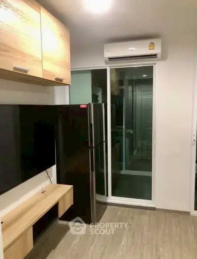 Modern living room with sleek design, featuring a large TV, air conditioning, and stylish wooden cabinets.