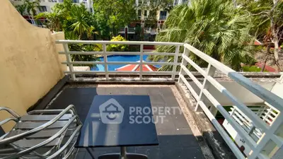 Charming balcony with pool view and lush greenery, perfect for relaxation and outdoor dining.